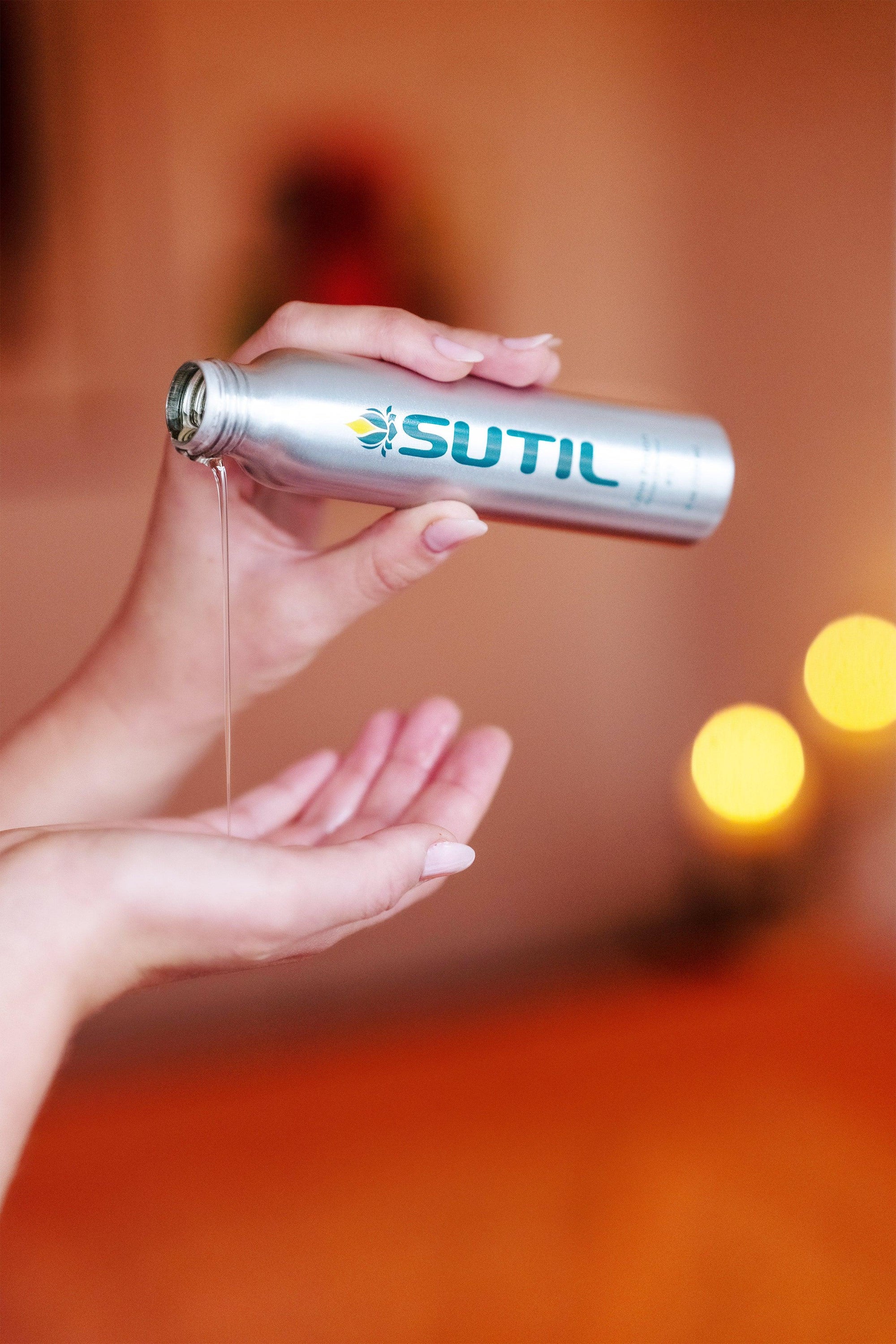Person pouring  SUTIL Massage Oil on their hand with a blurred background