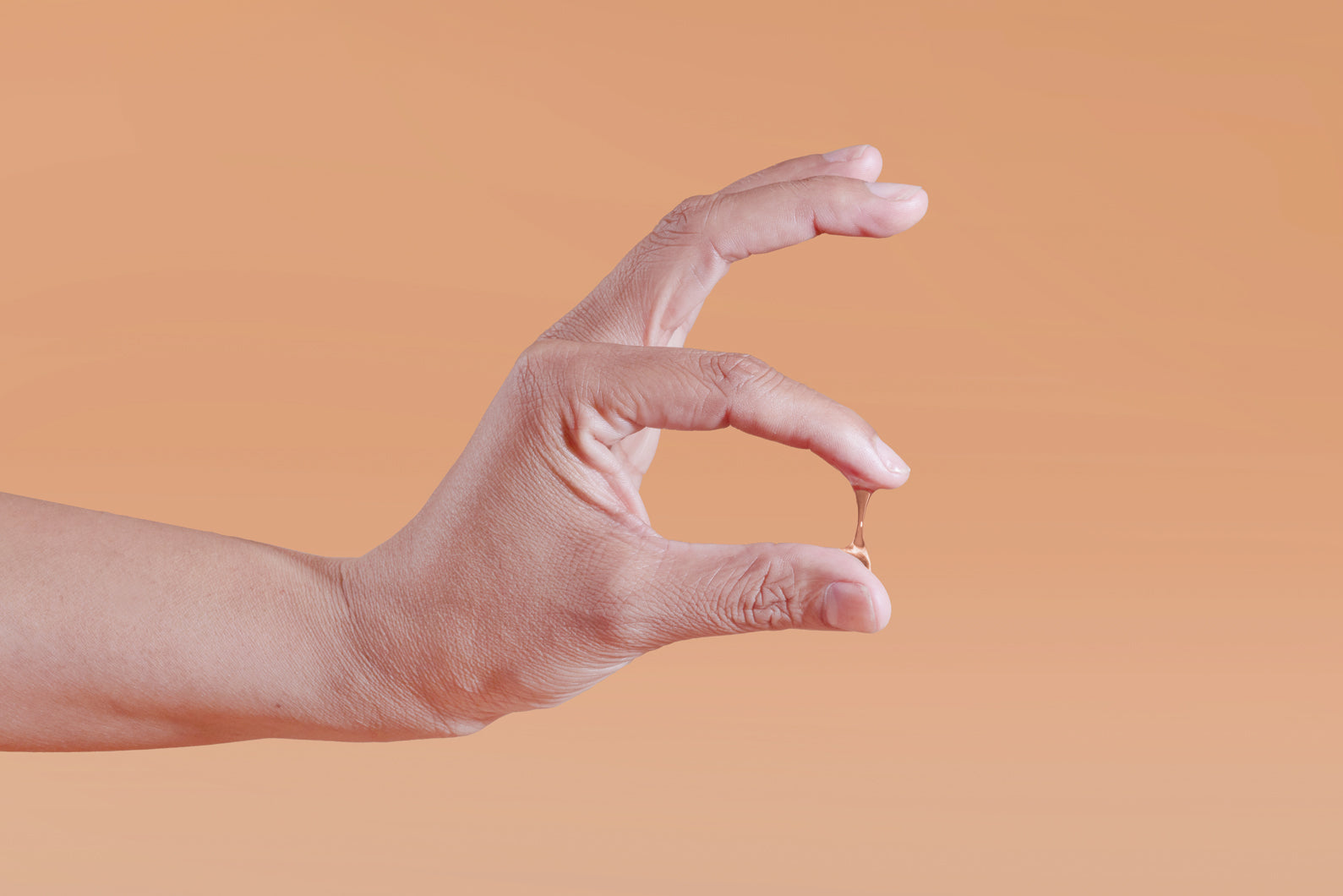 Hand showing Sutil Pure viscosity against a gradient orange background